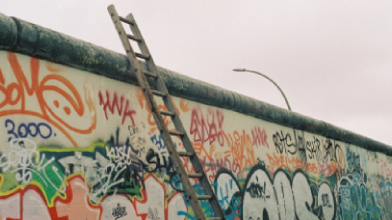 Eine Leiter lehnt an der Berliner Mauer.