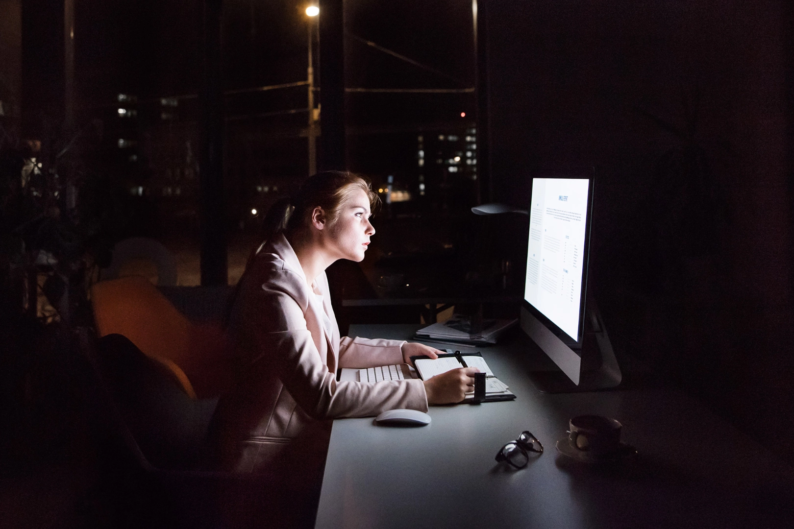 Geschäftsfrau vor Computer-Bildschirm im Büro in der Nacht