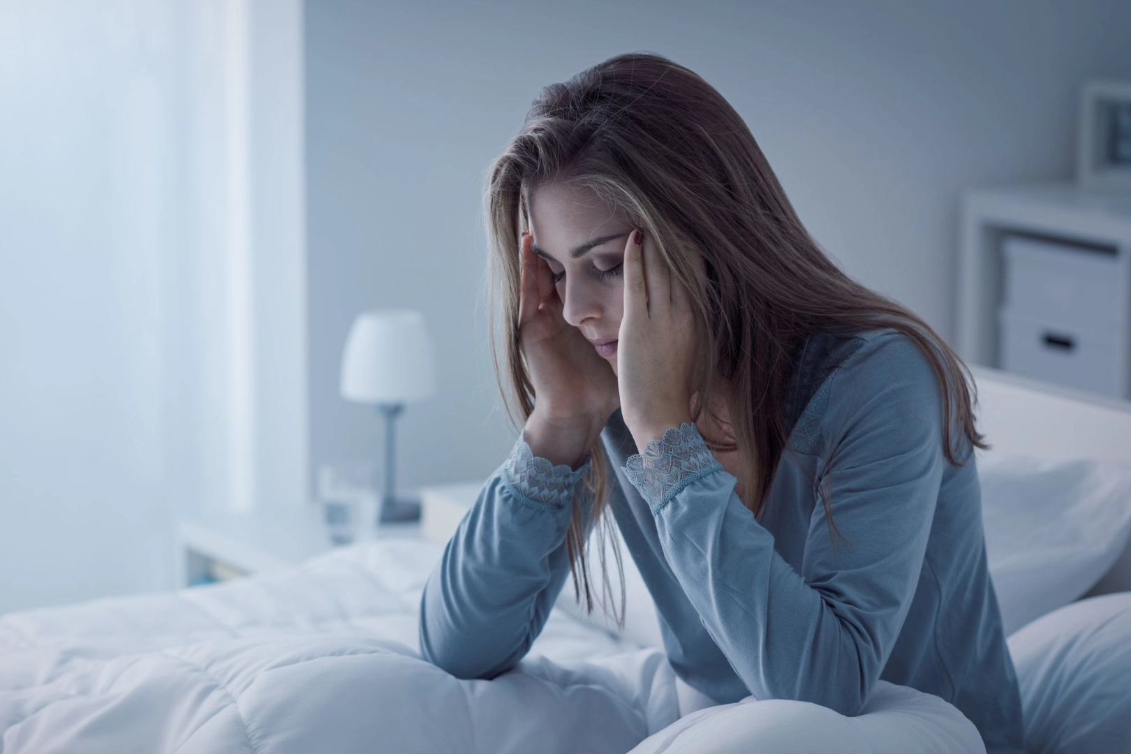 junge Frau sitzt müde in ihrem Bett