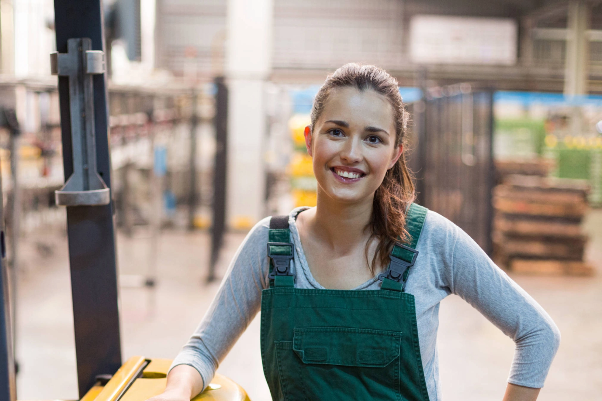 Eine junge Frau lehnt an einem Gabelstapler.