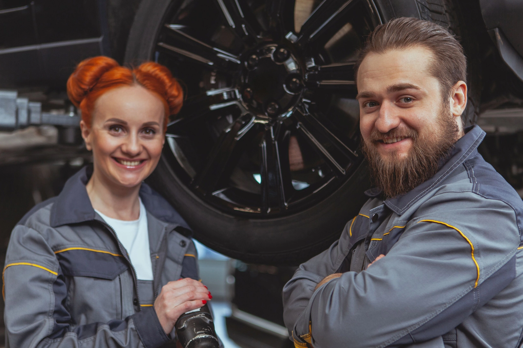 Eine Kfz-Mechanikerin und ein Mechaniker vor einem Auto