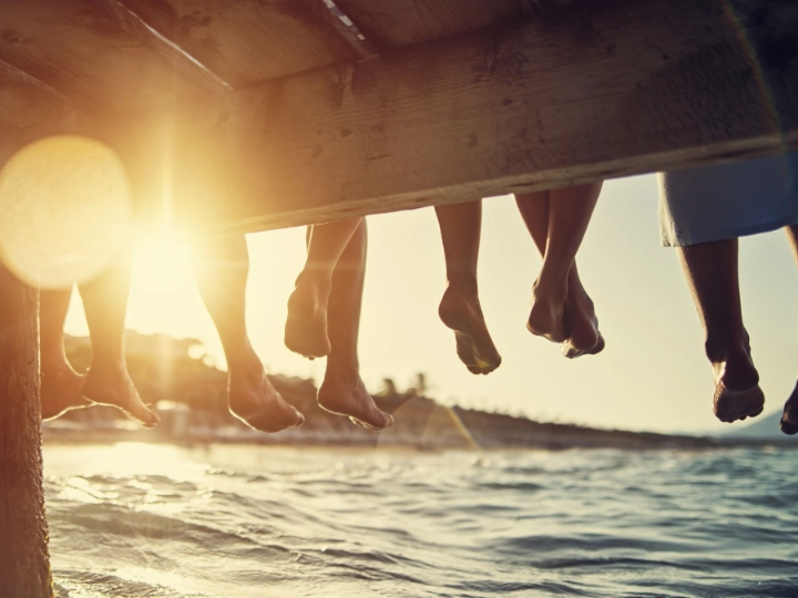 Familie sitzt bei Sonnenuntergang am Pier am Meer