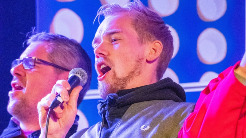 Ein junger Mann singt mit vollen Elan ins Mirkro