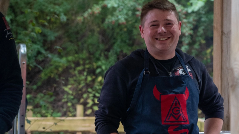 Ein Mann it Grillschürze am Grill